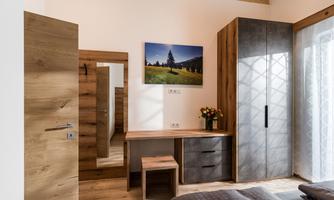 A modern room with wooden details and a desk. In the background hangs a picture of a landscape.