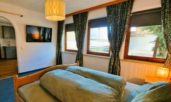 A cozy room with a bed and two pillows. Large windows let in plenty of light and offer a nice view.