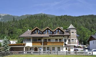 A modern building in a green landscape with mountains in the background. The sunny day and the clear blue skies give the scene an inviting atmosphere.