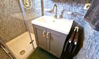 A modern bathroom with a shower and a sink. The walls are decorated with colorful tiles.