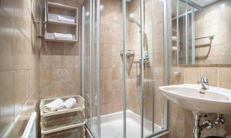 A modern bathroom with a glass shower and a sink. Towels are neatly stored in a basket.