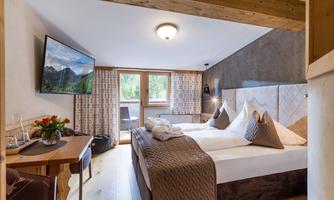 A cozy hotel room with a double bed and modern furnishings. Large windows offer a beautiful view of the surroundings.