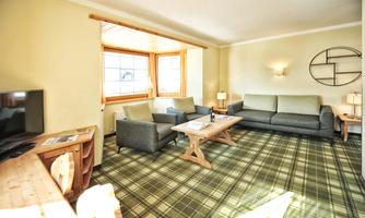 A bright living room with a gray sofa and two armchairs. Large windows provide plenty of natural light.