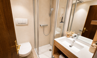 A modern bathroom with a shower, sink, and wooden details. The walls are bright and the room feels clean and inviting.