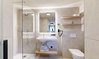 A modern bathroom with a shower, washbasin, and mirror. Bright colors and simple furniture create a pleasant atmosphere.