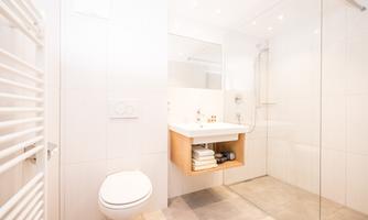 A modern bathroom with a shower, elegant sink, and bright tiles. The decor is friendly and clearly designed.