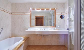 A modern bathroom with a bathtub and an elegant sink. The room is well-lit and has bright walls.