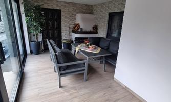 A bright, modern living room with comfortable seating and a table. A plant enhances the cozy atmosphere of the room.