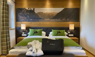 A cozy hotel room with two beds and modern amenities. The walls are decorated with wooden paneling and a beautiful landscape motif.