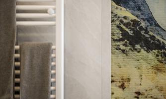 A towel warmer with gray towels in a bathroom. In the background, there is a colorful wall with mountain motifs.