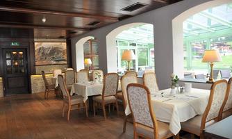 An elegant restaurant with wooden floors and inviting tables. Large windows let in plenty of daylight and offer a view outside.