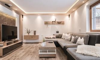Modern living room with a large, comfortable sofa and a television. Soft lighting and simple decor create a cozy atmosphere.