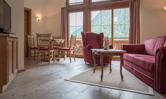 A cozy living space with a red sofa and a small table. Large windows offer a view of the mountains.