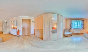 A bright and cheerful room with two beds and orange cushions. In the background, there is a mirror and a window with curtains.