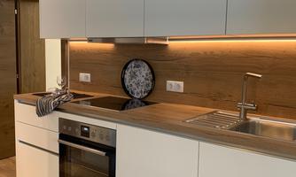 A modern kitchen with bright cabinets, a sink, and a cooktop. The wood paneling gives the kitchen a warm atmosphere.
