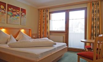 A cozy room with a double bed and a table.  
Large windows let in plenty of light and offer a view outside.