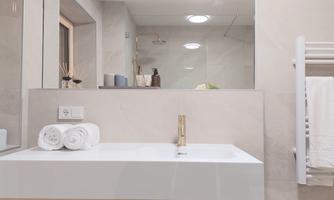 A modern bathroom with a white sink and fresh towels. The walls are light and the space feels clean and inviting.