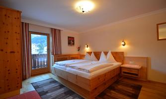 A cozy bedroom with wood interiors and a large bed. There is a balcony with a view and a pleasant atmosphere.