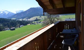 A balcony overlooking a green meadow and mountains in the background. The landscape is picturesque and exudes tranquility.