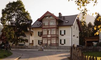A charming building in a rural style with red accents and large windows. Surrounded by trees and a quiet street.