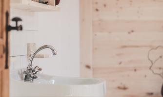 A modern bathroom with a white sink and a red towel. The walls are made of light wood, creating a cozy atmosphere.