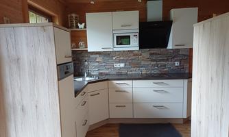 A modern kitchen with bright cabinets and an elegant stone wall. It is well-lit and has a cozy atmosphere.