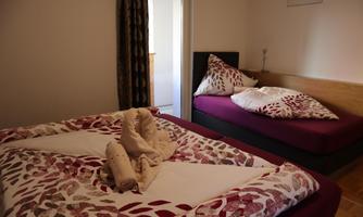 A cozy bedroom with two beds. The bedding has an attractive pattern in red and white.