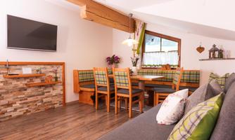 A cozy living space with a dining area and a modern kitchen. Bright colors and wooden details create an inviting atmosphere.