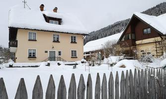 A pretty house in the snow with a white fence. Winter has transformed the landscape into a calm, snowy environment.