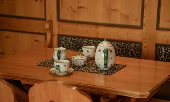 An elegant tea set on a wooden table. The cups and the teapot are decorated with beautiful patterns.