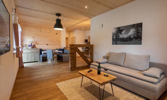 A modern living room with a comfortable sofa and a small table. The room has wooden floors and a warm, inviting atmosphere.