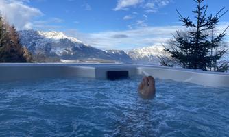 A relaxing panorama with a hot tub and stunning mountains in the background. The clear air and water invite you to unwind.