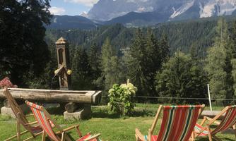 A beautiful view of the mountains with comfortable loungers in the foreground. The landscape is green and surrounded by trees.