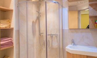 A modern bathroom with a glass shower and a beautiful sink. There are shelves with colorful towels and it is well illuminated.