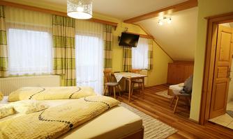 A cozy bedroom with two beds, a table, and chairs.  
Large windows provide plenty of daylight and a welcoming atmosphere.