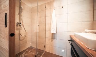 A modern bathroom with a walk-in shower and bright tiles. A towel hangs next to an elegant sink.