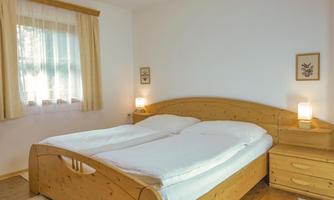 A cozy bedroom with a large wooden double bed. The walls are brightly painted and the room is well lit.