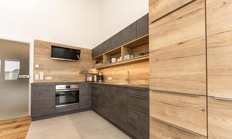 A modern kitchen with wood and gray tones. It is well-equipped and offers plenty of storage space.