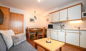 A cozy apartment with a modern kitchen area and a dining area. The room is bright and cheerfully furnished.