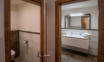 A well-equipped bathroom with two mirrors and modern fixtures. On the left, a separate toilet is visible.