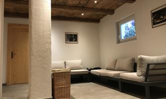 An inviting room with bright walls and a wooden beam ceiling. Comfortable seating and a friendly atmosphere make the room cozy.