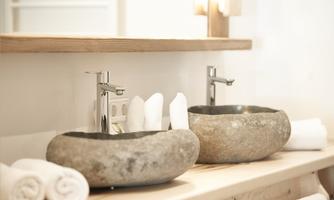 Two elegant stone sinks on a wooden surface. Towels and modern faucets complement the stylish bathroom design.