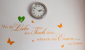 A wall hanging with a quote about love and food decorates the room. Above it hangs a silver wall clock.