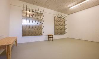 A blank room with two large pegboards and a small table. The walls are painted in neutral colors, and the floor is simple and unobtrusive.