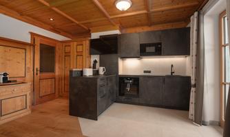 A modern kitchen design with wood and dark metal accents. The kitchen is well-lit and features high-quality appliances.