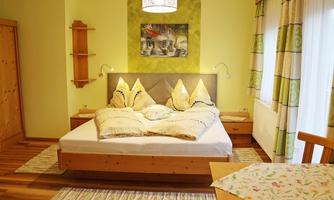 A cozy bedroom with a large bed and decorative pillows. The walls are in soft colors and the room has an inviting ambiance.