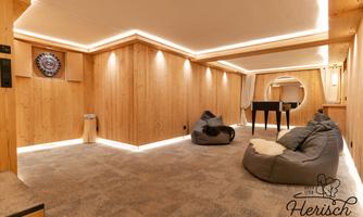 A cozy room with wooden paneling and soft bean bags. In the corner, there is a dartboard and a piano.