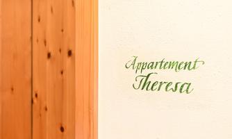 A wooden door that leads to an apartment. Next to it is the inscription "Appartement Theresa" on the wall.