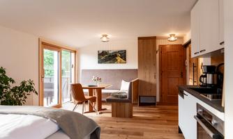 A modern and cozy living and bedroom with wooden flooring. 

Large windows let in plenty of light and provide access to the terrace.