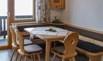 A cozy dining area with a table and four wooden chairs. The walls are bright and there is a window with a view to the outside.